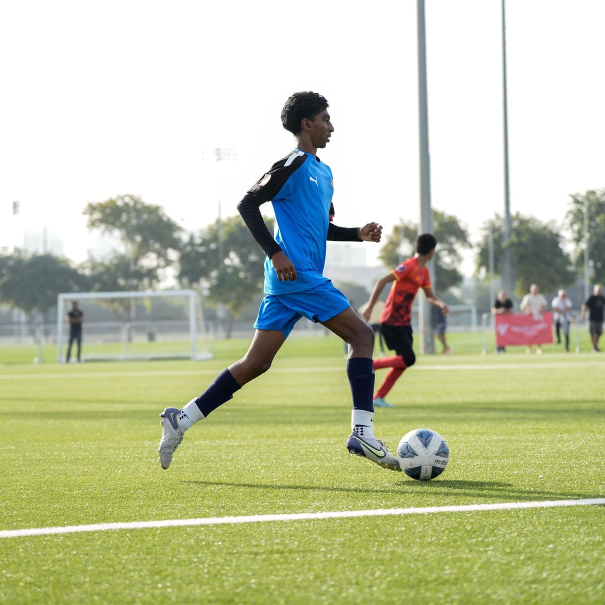 A young footballer on turf in daylight.