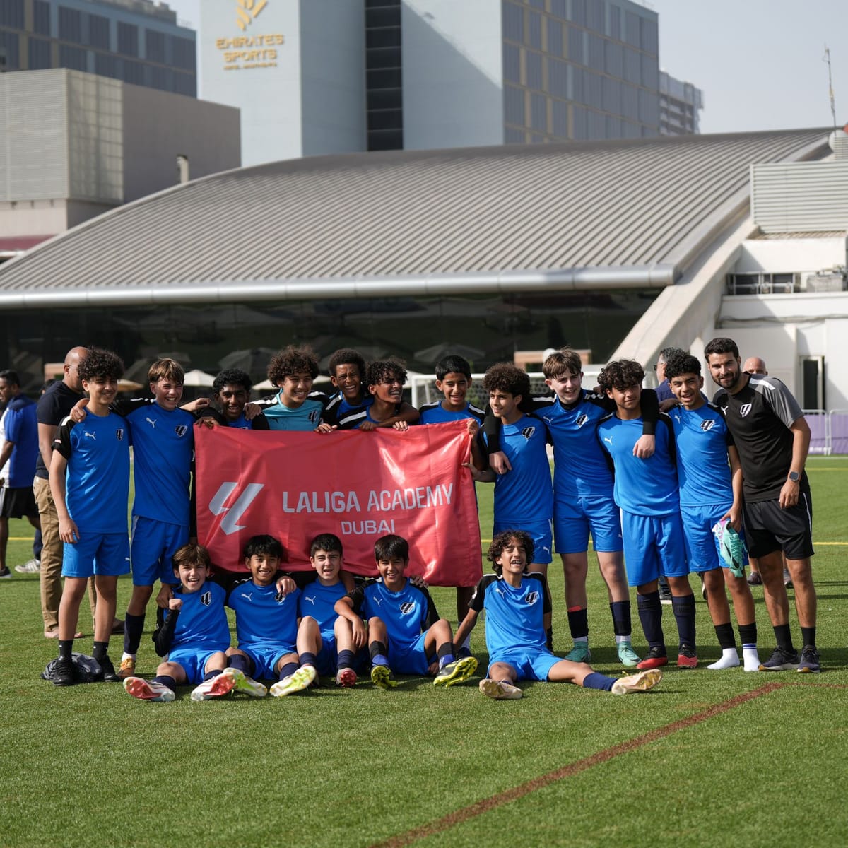 The curved silver roof of the hall at Sports Village, seen behind a squad on the pitch.